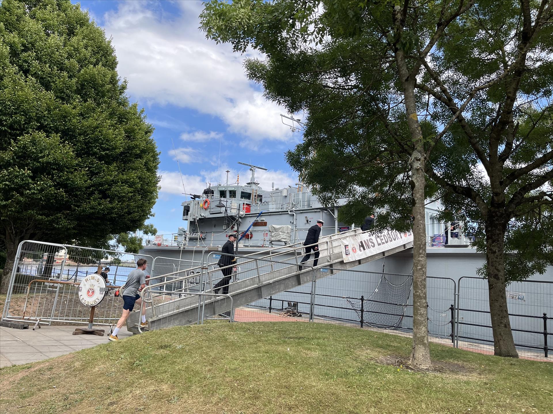 A battleship-grey ship behind green trees