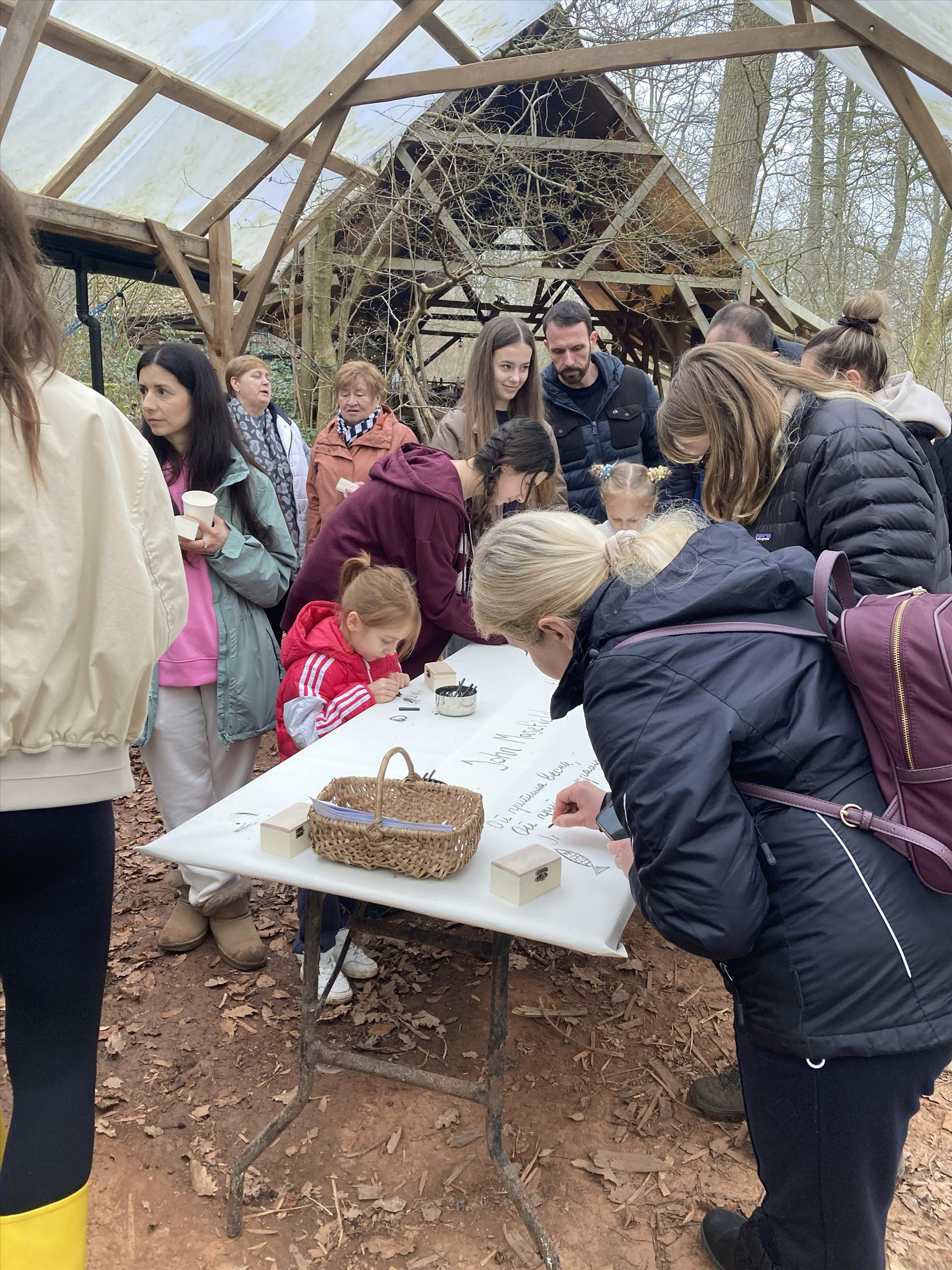 A cluster of people of different ages drawing on a large piece of paper.