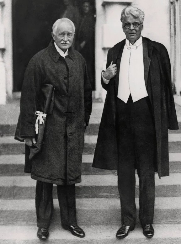 A black and white photograph of John Masefield and WB Yeats, two middle-aged white men wearing formal attire. 